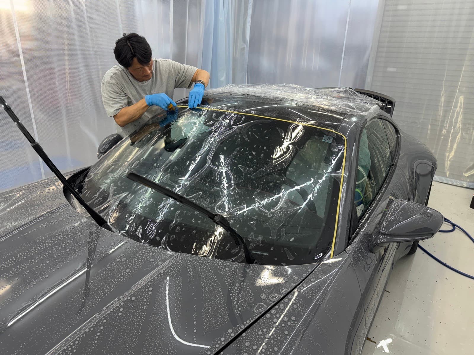 鈴木智也 代表取締役がフロントガラスにフィルムを貼っているところ|料金 福井市 アニマートカーメンテナンス
